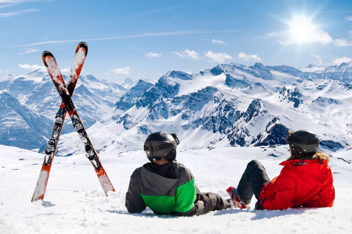 Deux skieurs couchés dans la neige et des skis plantés debout